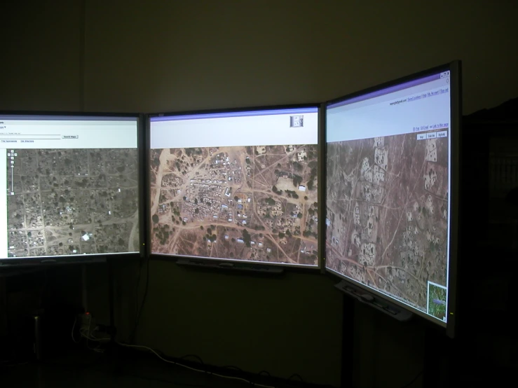 two computer monitors sitting on a desk displaying a map