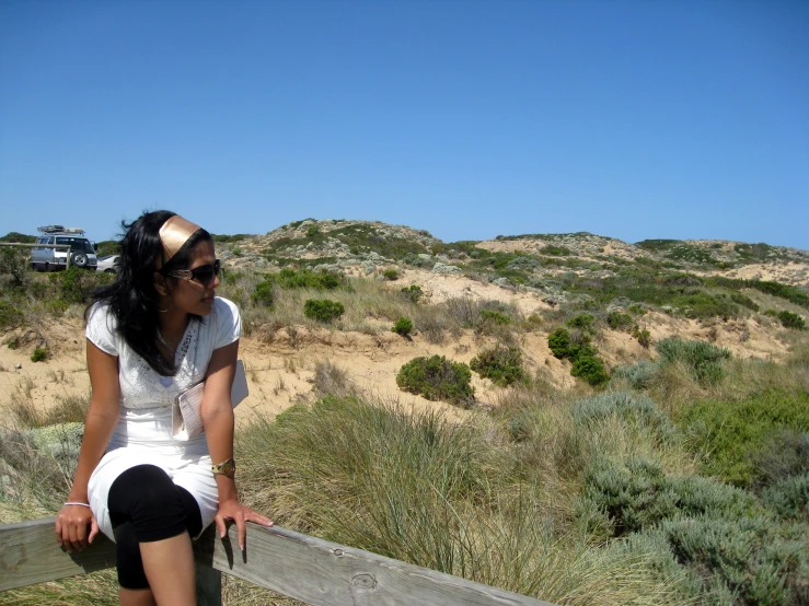 woman in white shirt sitting on a wooden railing