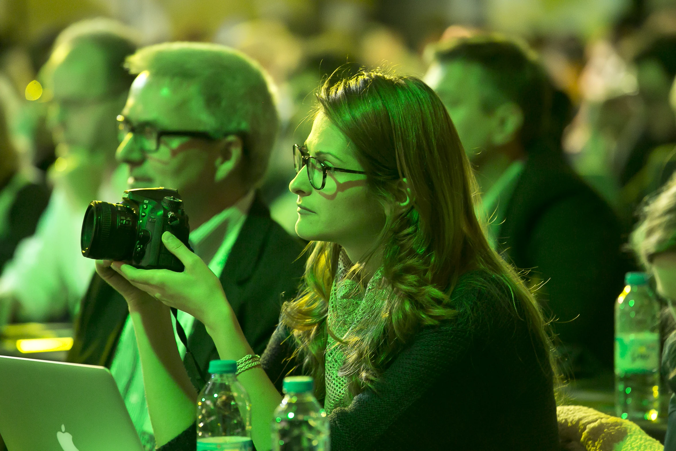 woman taking picture with camera as audience looks on