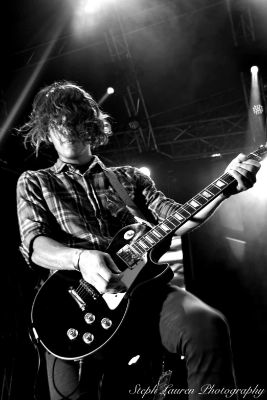 a man with curly hair playing a guitar on stage