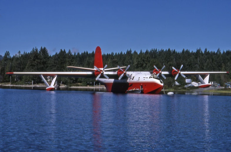 a big water plane is parked at the edge of a lake
