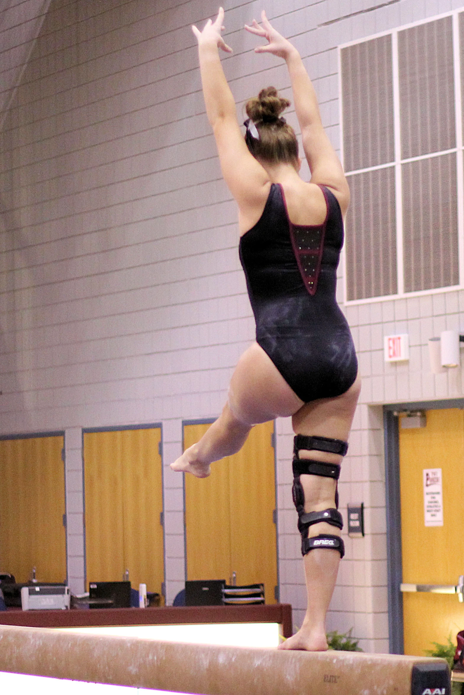 a woman in tights is standing on top of a beam