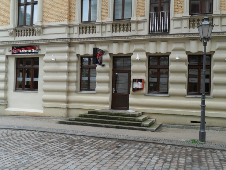 a bricked city street corner with two older buildings in the background