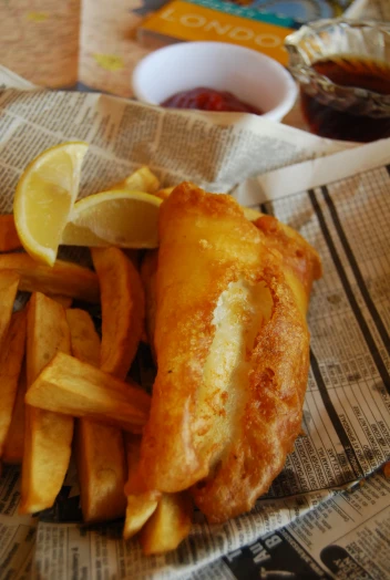 fish and chips served on a newspaper with syrup