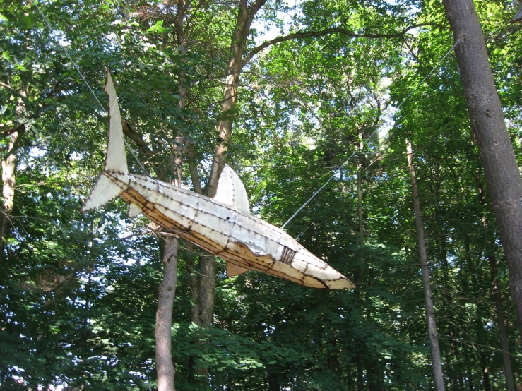 a plane hanging from the trees in a wooded area