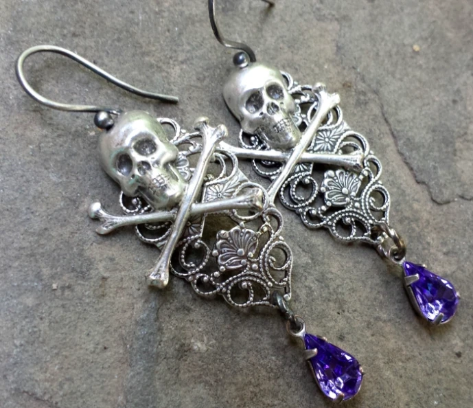 three skull with crossbones and jewels attached to earrings