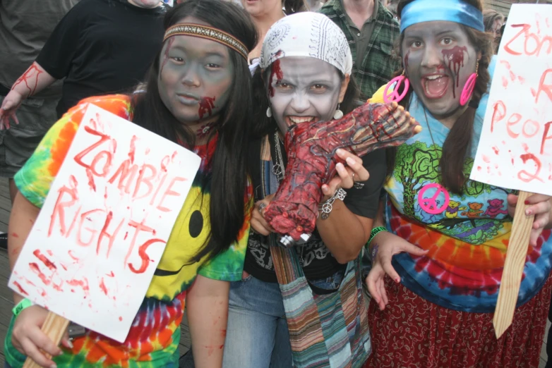 a group of people dressed up like zombies holding signs