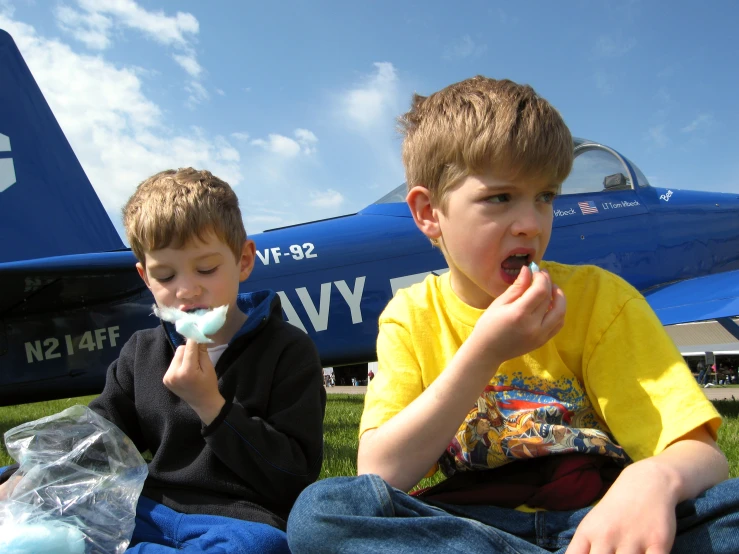 two children sitting in the grass outside while eating soing