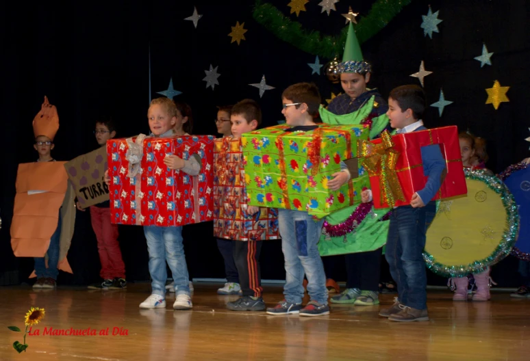 several small children holding presents while wearing costumes