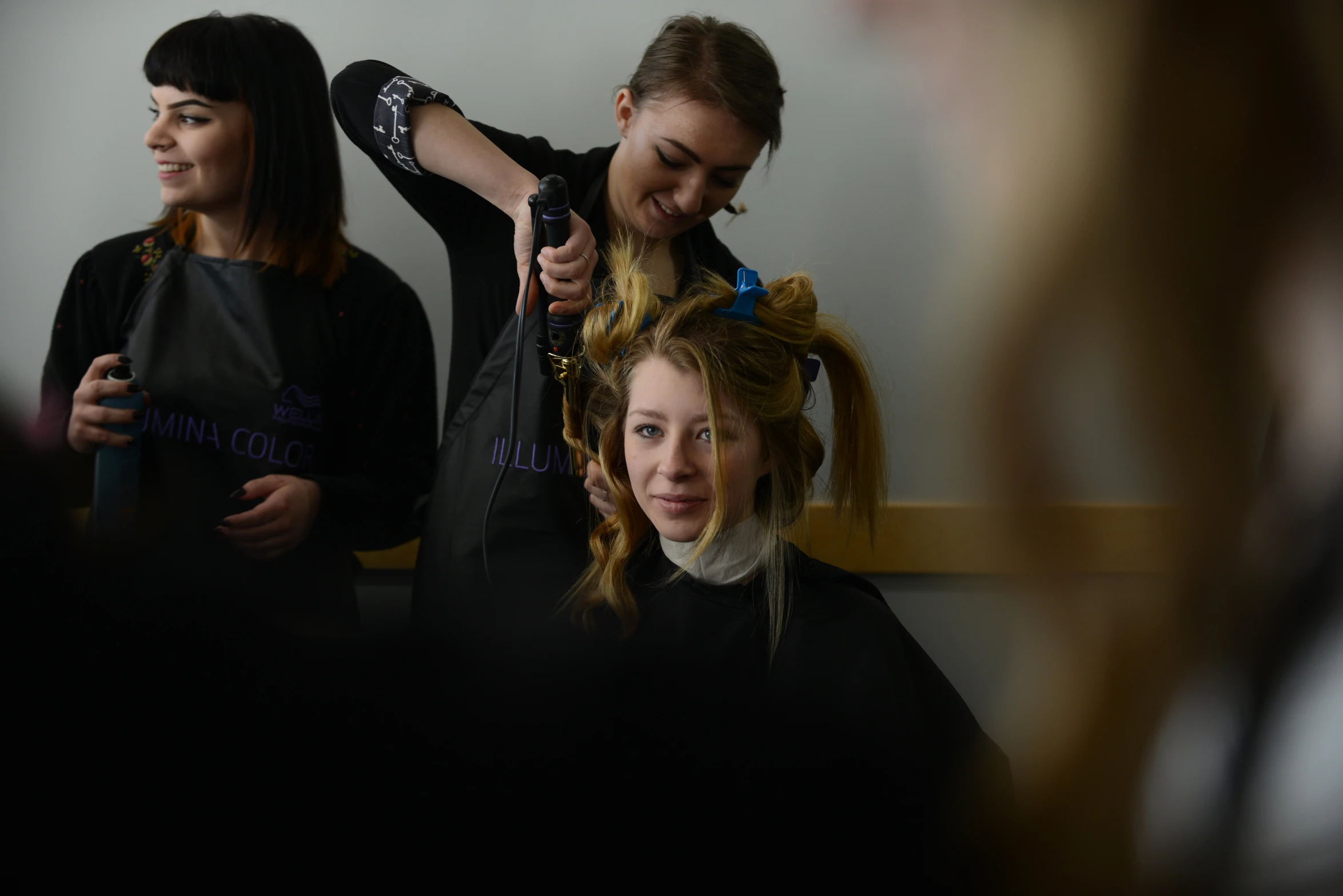 a girl is having her hair styled while another girl watches