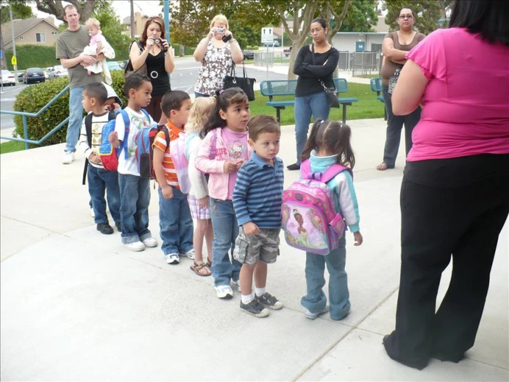 a group of children with their school backpacks lined up at the park