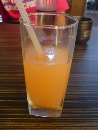 an orange drink in a clear glass with a straw