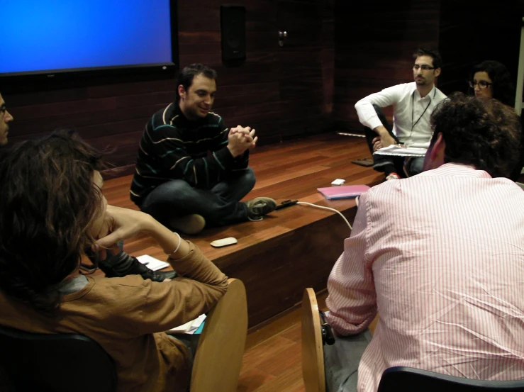 a group of people sit on a stage and watch some of the men