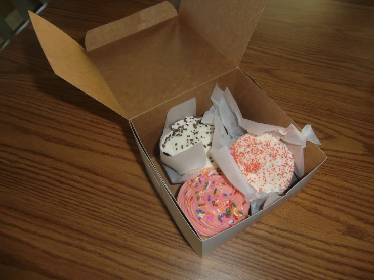 two pink and one white doughnuts in a box