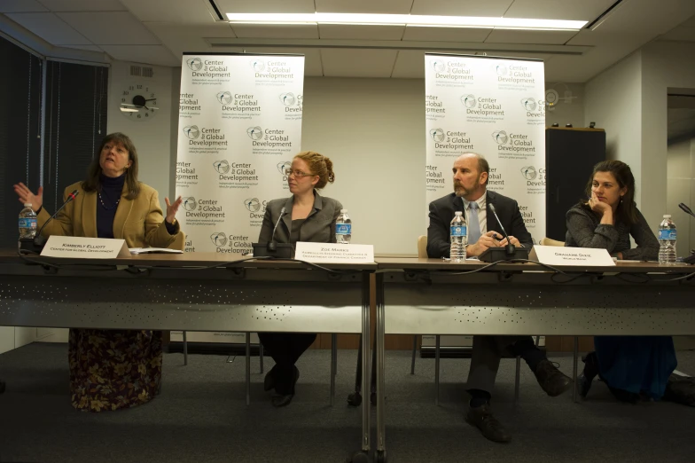 four people sitting at a table with microphones