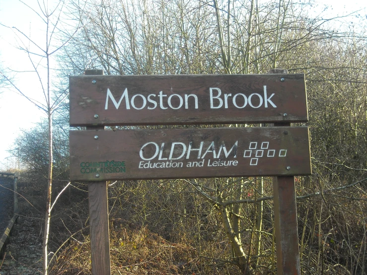 a wooden sign next to some trees in the woods