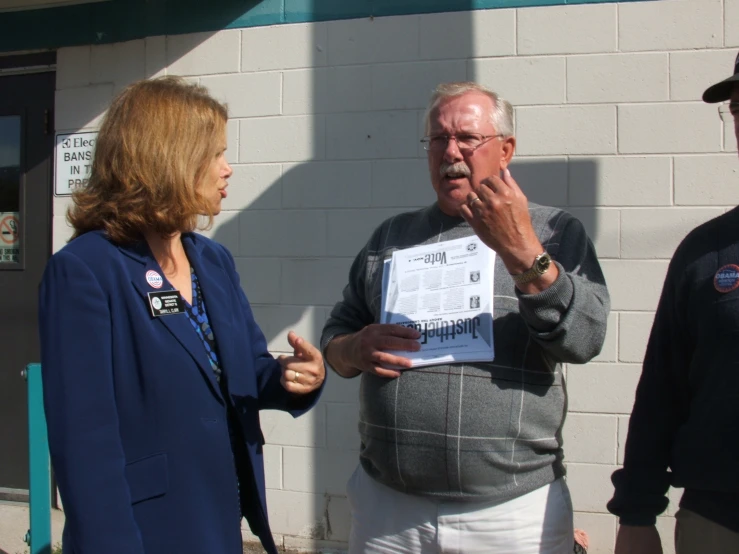 two men standing near each other talking to an older woman