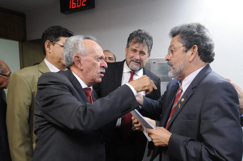 a man giving another man a tie and talking to another man