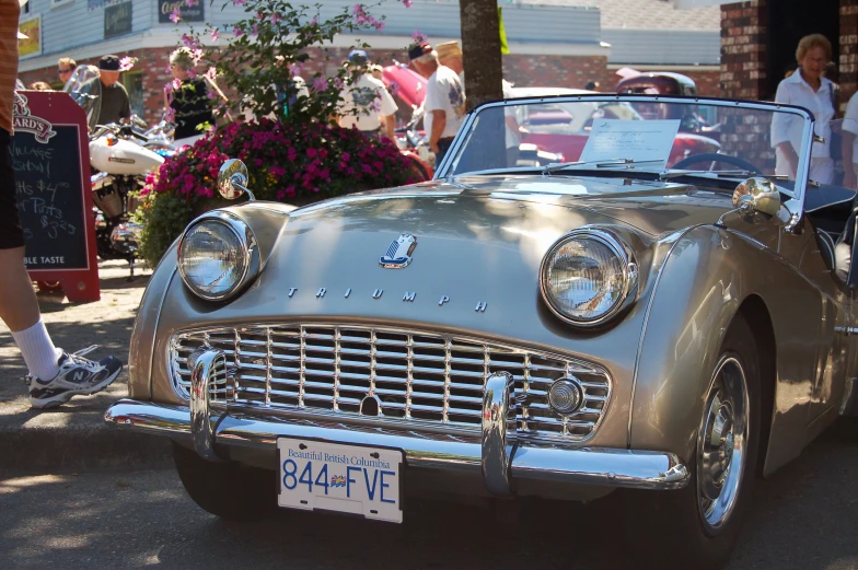 an older car parked on a sidewalk at an antique vehicle show