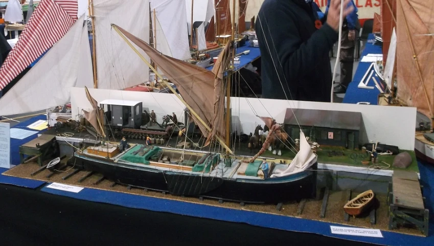 a model boat on a table, with people working around it