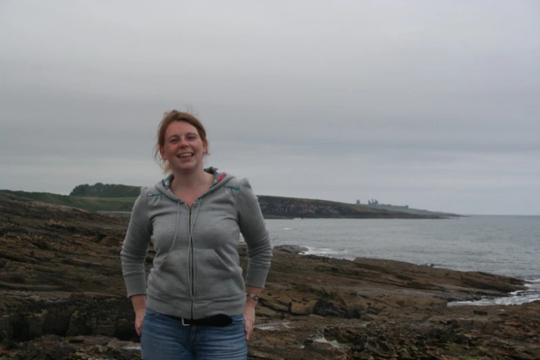 a person standing near the ocean with a cloudy sky