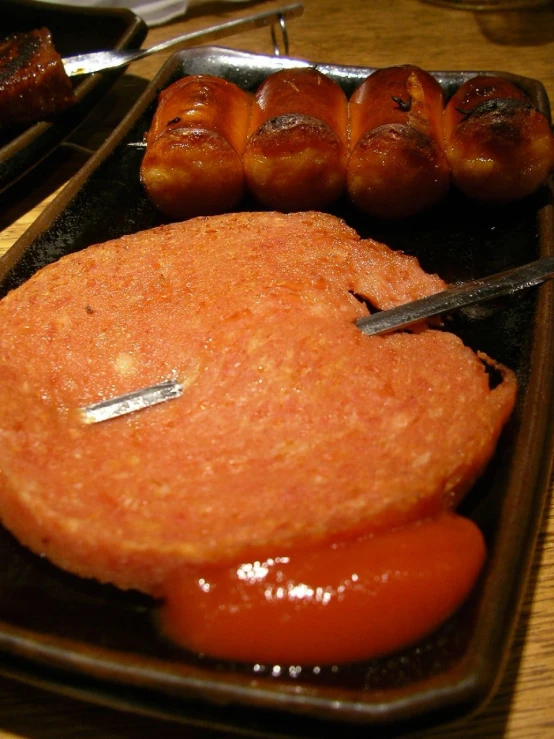 a sausage covered in sauce sits beside some sausages