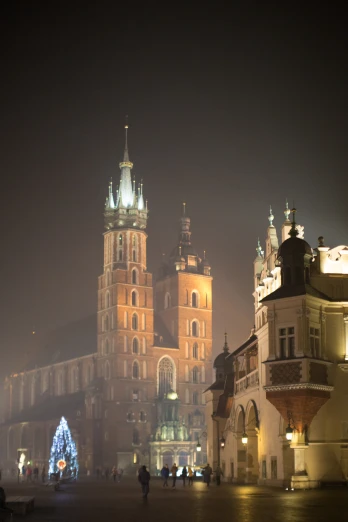 a castle on a foggy night with people walking by