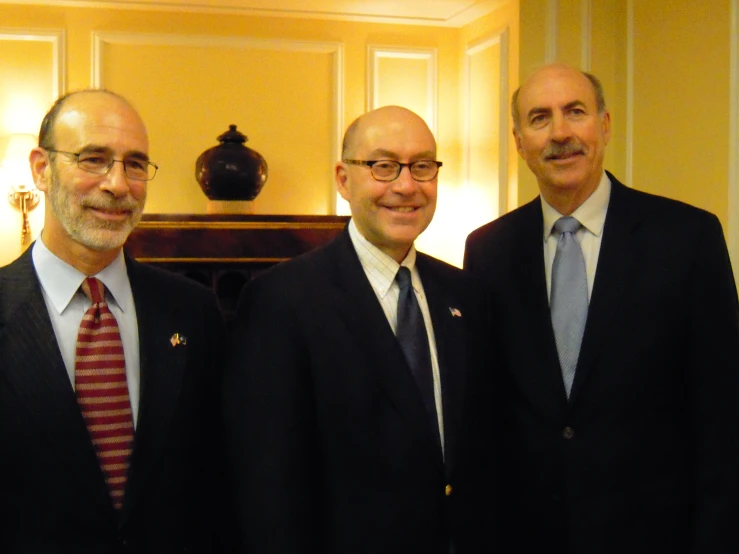 three men in suits are standing in a room