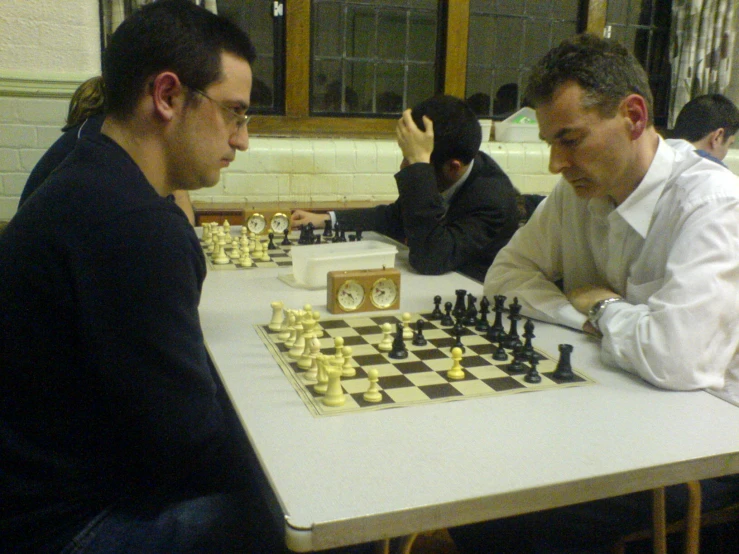 a man plays chess as another watches his