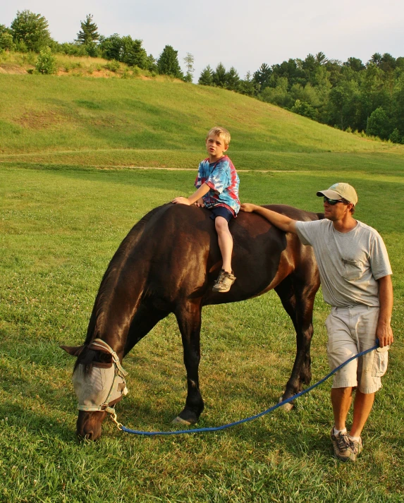 a man standing next to a little girl on top of a horse