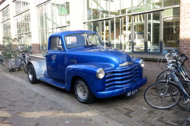 an old blue truck sitting on the side of a building