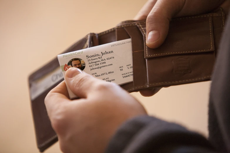 a man is holding out his id card and a wallet