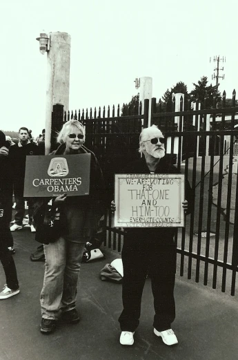 a group of people hold up signs while on a sidewalk