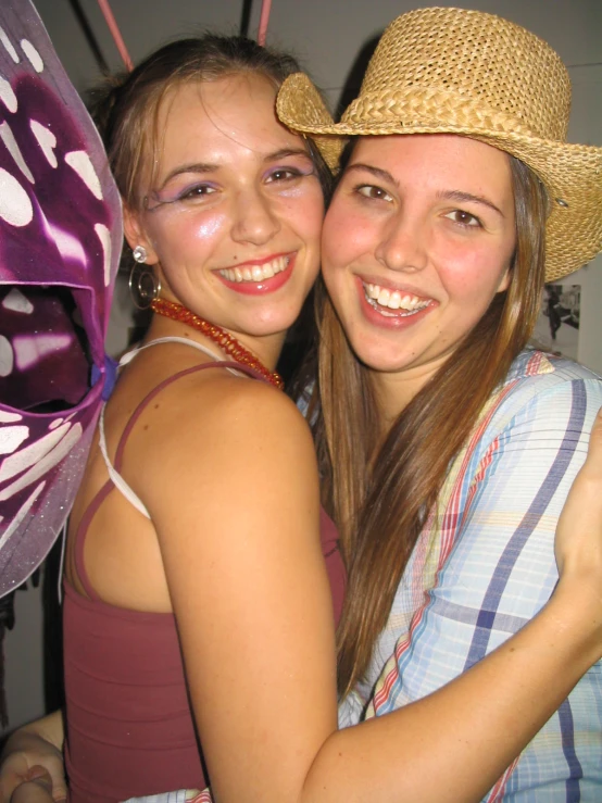 two girls smiling and hugging with a kite in the background