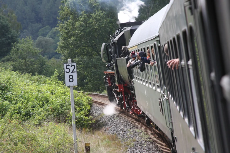 a man riding on the side of a train and waving