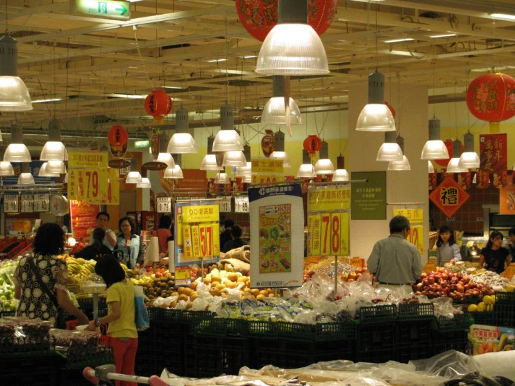 people walk around in a market with lots of produce