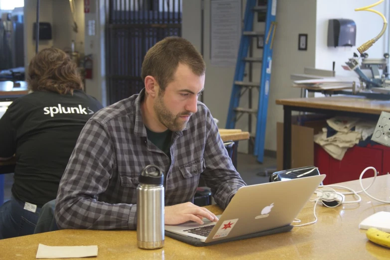 a man sitting at a table in front of a laptop