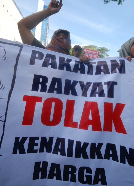 a protest sign written in different languages and on a person holding up a fist