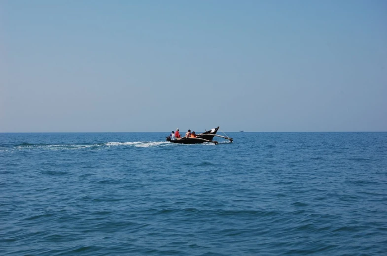 three people ride a boat in the ocean