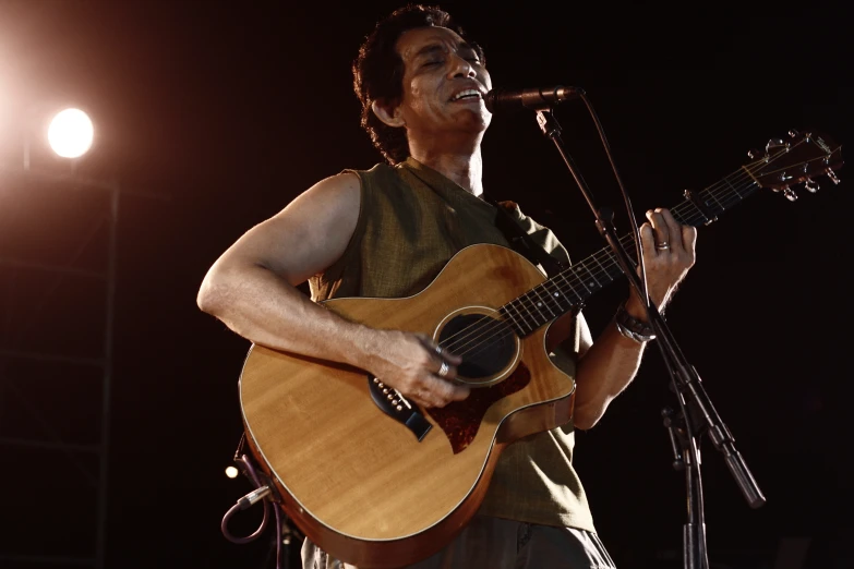 a man standing with a guitar while he sings