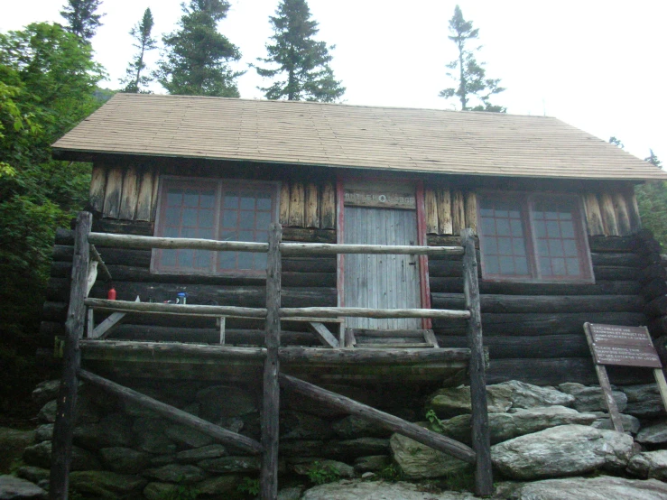 a wooden log cabin sitting on top of a rocky hillside