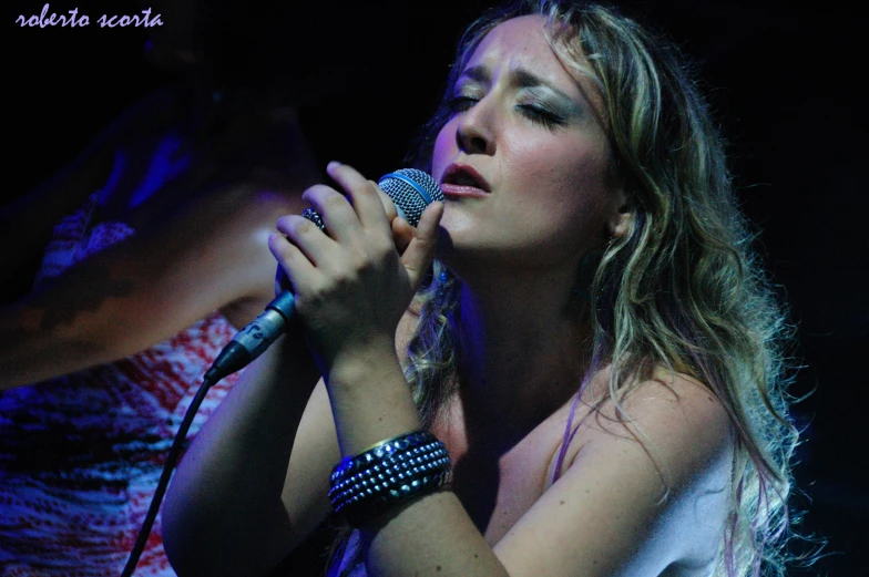a female singer in a white shirt holding a microphone
