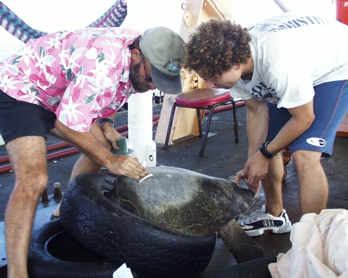 two men are using tires to put them in a container