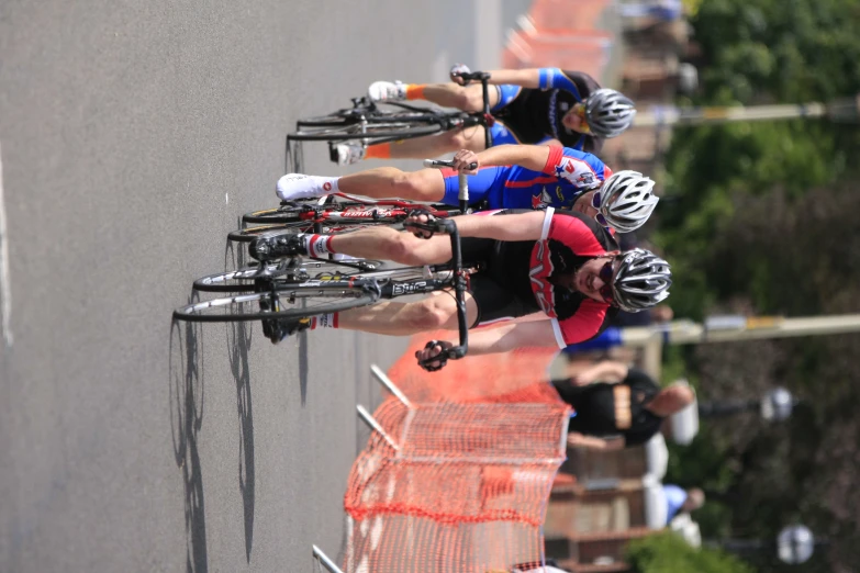 three people riding bicycles on a road next to barrier