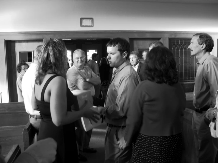 black and white po of people standing in a church with one of them talking