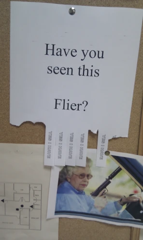 papers, a clipboard, a sign, and other clutter are arranged on the wall