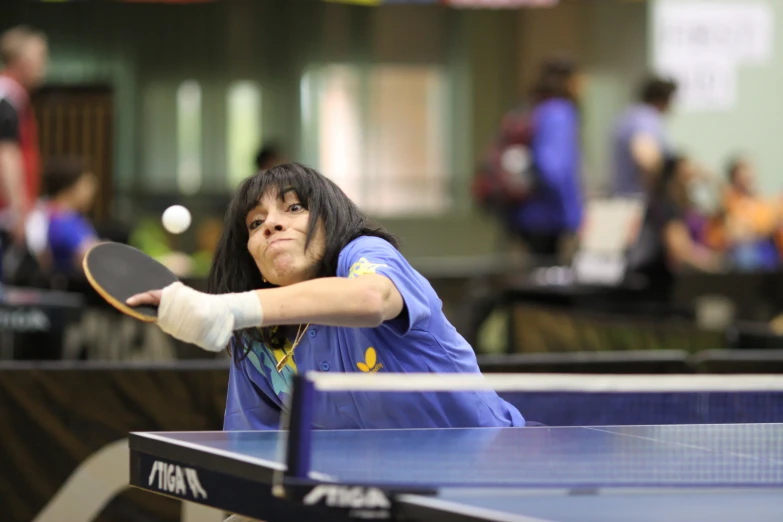 a female ping pong player hits the ball back to her opponent
