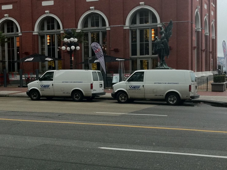 two white delivery trucks parked side by side in front of a building