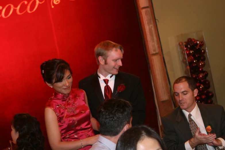 man and woman in red dress holding up their cellphones while two others watch