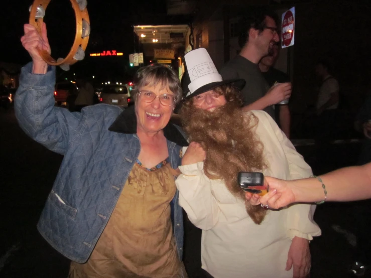 two ladies, one holding a fake beard and the other wearing a large fake moustache